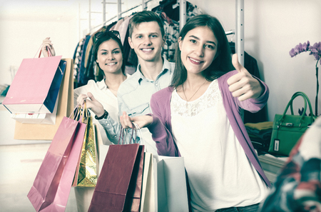 Guy and two girls holding bags with clothes in discount storeの写真素材