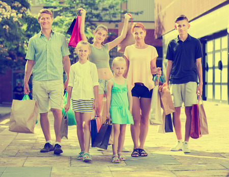 Smiling young parents with four kids gladly shopping in townの写真素材