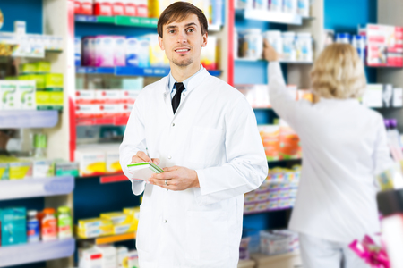 Happy pharmacist and pharmacy technician posing in drugstoreの写真素材