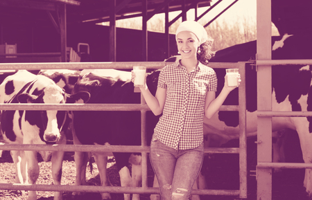 Young cheerful woman farmer showing fresh milkの写真素材