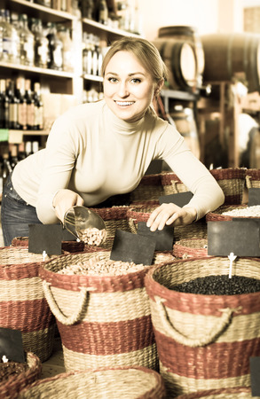 Positive female customer selecting dried beans in shopの写真素材