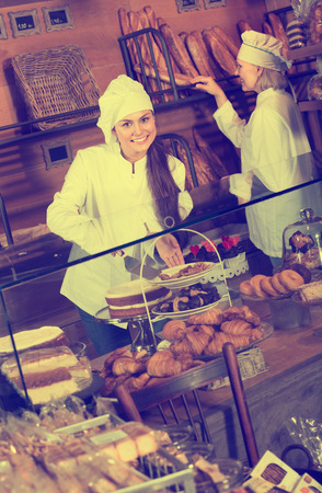 Bakery staff posing with bread and different pastry for saleの写真素材