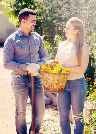 smiling young woman holding basket with orange flowers together with mature man. Focus on manの写真素材