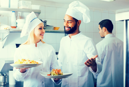 Crew of positive european professional cooks working at restaurant kitchenの写真素材