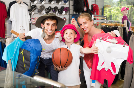smiling russian man and woman with boy choosing all for hiking in sport shopの写真素材