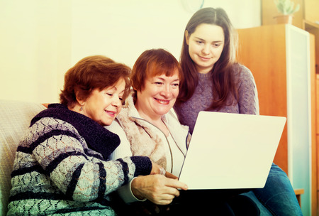 Mature women and happy girl with laptop at homeの写真素材