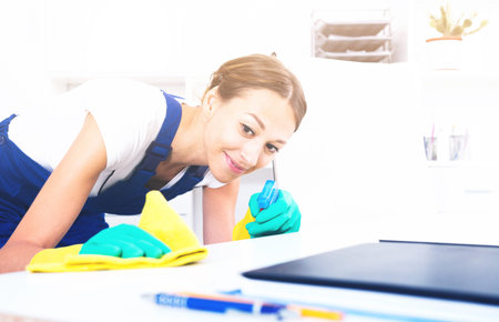 smiling woman in protective coveralls cleaning at office
