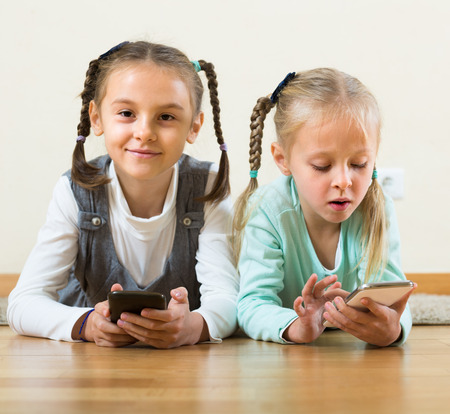 girls 4-5 years old playing with smartphones at homeの写真素材