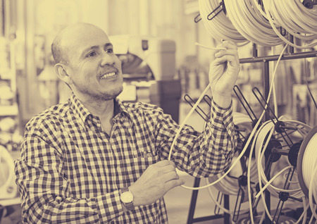 Ordinary senior man looking at cable in household storeの写真素材