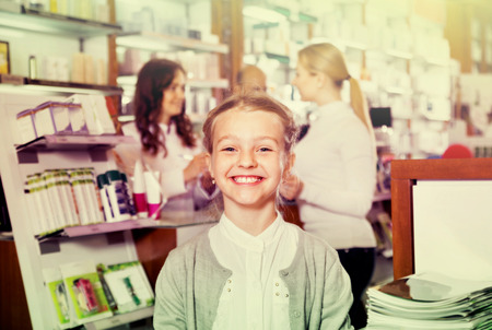 Little  girl holding a product box in the pharmacy with parents and pharmacist on the backgroundの写真素材
