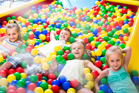 small american children playing together in pool with plastic multicolored ballsの写真素材