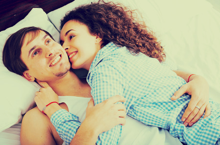 Happy man and woman lying in bed with smileの写真素材