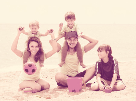 Happy parents with three children at the weekend on the beachの写真素材