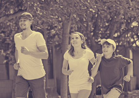 Positive parents with son running in park at summer dayの写真素材