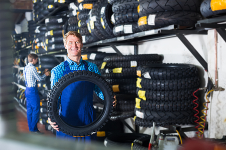 Two professional colleagues working with motorcycle tires in service pointの写真素材