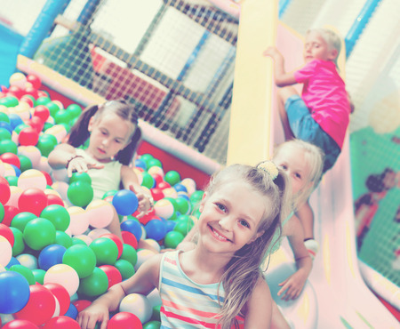 Small girl in elementary school age playing with multicolored plastic ballsの写真素材