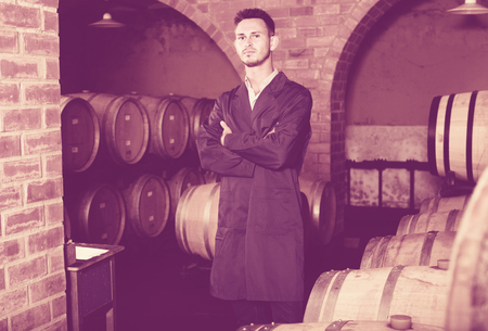 portrait of young male wine maker in coat working in winery cellarの写真素材