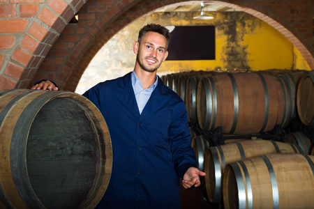 portrait of smiling male wine maker in coat working in winery cellarの写真素材