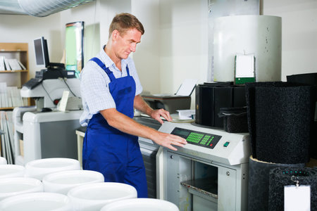 concentrated man seller wearing uniform standing with goods lift in housewares hypermarket