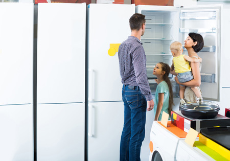 smiling american  family of four shopping new refrigerator in home appliance storeの写真素材