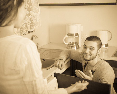 Repairman repairing a running water for housewifeの写真素材