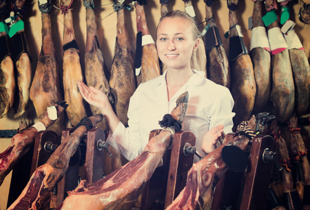 Portrait of adult female working in meat shop with delicatessen dried hamの写真素材