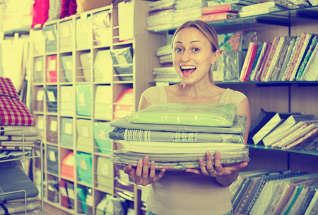 Happy housewife buying bedding set in home textile boutiqueの写真素材