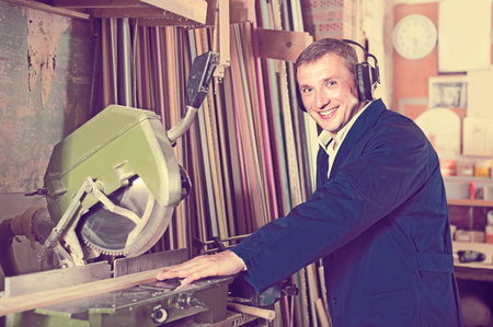 portrait of happy american  man in uniform working on electrical rotary saw indoors