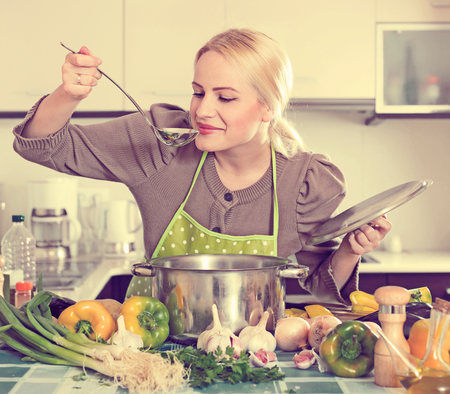 Happy girl in apron with vegetables at kitchenの写真素材