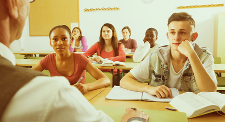 Group of multiethnic students listening a teacher with attention at the lecture in the classroomの写真素材