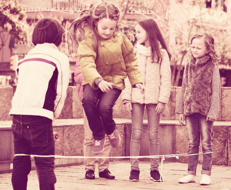 Active children playing rubber band jumping game and laughing outdoorsの写真素材