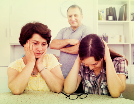 Sad young woman talking to mature parents and getting help and support in the home. Focus on mature and young womenの写真素材