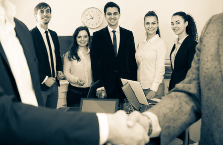 Two managers shaking hands at business meeting in office