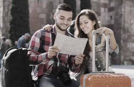 Happy couple in casual clothes with trunk and backpack outdoor