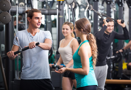 Friendly young people doing powerlifting on machines in gymの写真素材