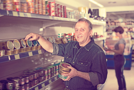 Portrait of man buying a preserves at the grocery storeの写真素材