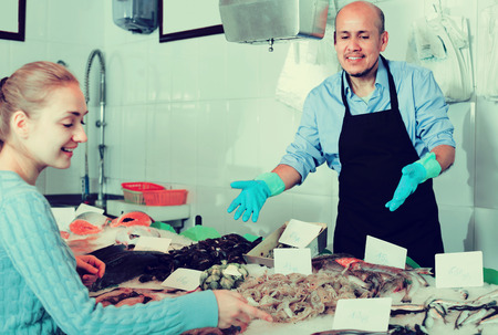 Young smiling blonde woman selecting cooled fish at fisheryの写真素材