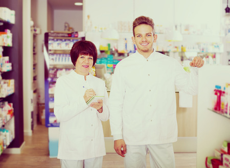 Smiling pharmacist and pharmacy technician posing in drugstoreの写真素材