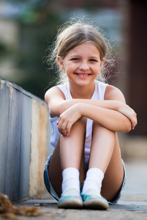 smiling girl in elementray school age sitting outdoors on summer dayの写真素材