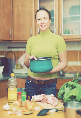Happy young housewife preparing meal at home and smilingの写真素材