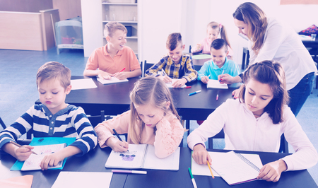 Professor and elementary age children at the classroom in a schoolの写真素材