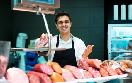 Portrait of male seller offering wursts in local butchery