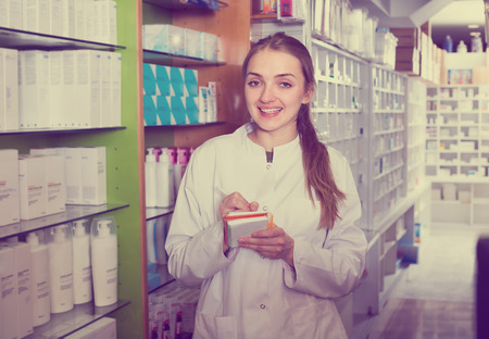 Friendly young female technician in white overall working in chemist shopの写真素材