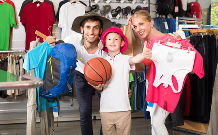 smiling european  man and woman with boy choosing all for hiking in sport shopの写真素材