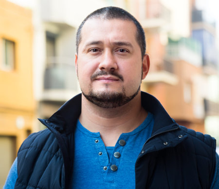 Portrait of attractive man standing on street in a blue jacket and a blue vest