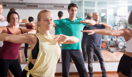 Young happy people studying dancing elements in dancing hall
