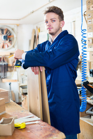 Young male worker checking measurements for furniture at workshopの写真素材