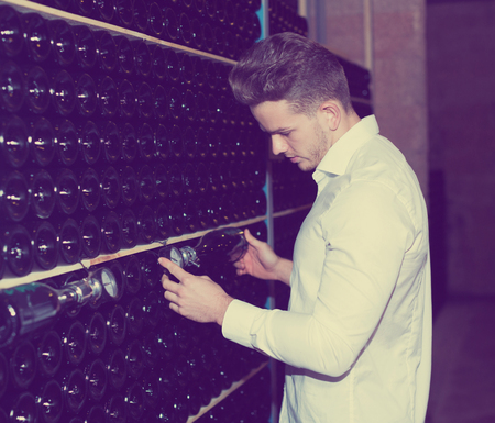 Male employee observing secondary fermentation of wine at sparkling wine factoryの写真素材