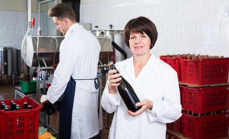 Woman worker corking sparkling wine with machine at wine factoryの写真素材