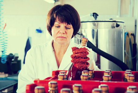 Glad female employee packing wine bottles at sparkling wine factoryの写真素材
